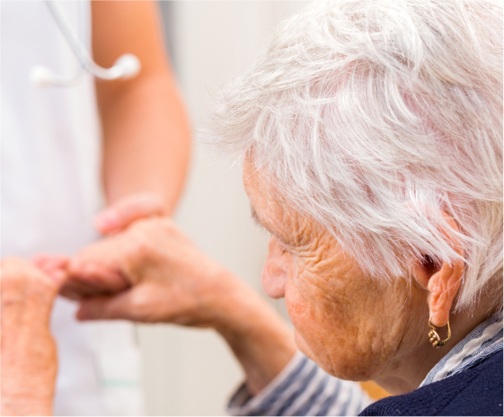 Женщина с болезнью Альцгеймера держится за руки медсестры