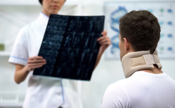 Врач смотрит рентген-снимок шейного отдела мужчины